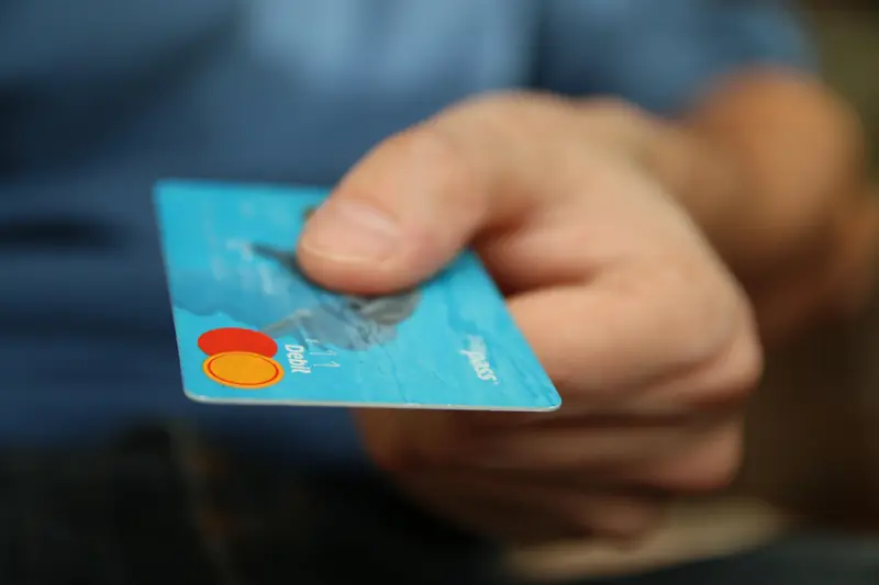 Hand reicht eine Bankkarte weiter, Symbolbild für Kartenmissbrauch